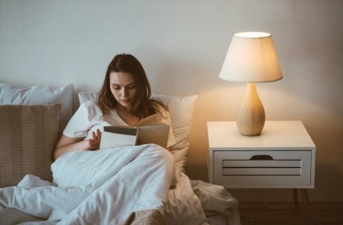 Yatağında kitap okuyan bir kadın