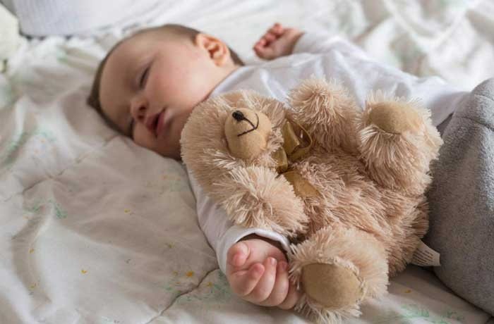Yanında oyuncak ayısı olan uyumuş bir bebek