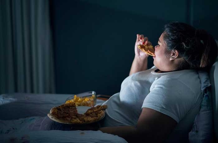 Gece yatağında yemek yiyen şişman bir kadın