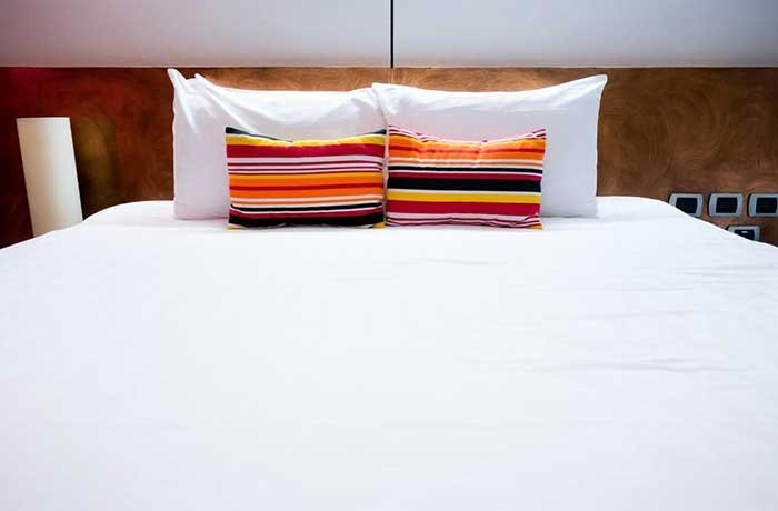 Beyaz bir yatak örtüsü ve renkli yastıklar