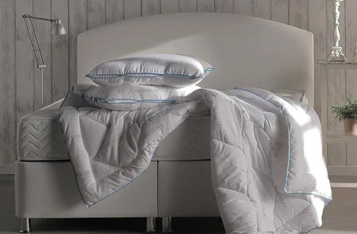 Beyaz bir yatakta iki yastık ve bir yorgan