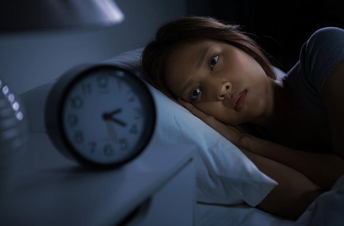 Yan uyku pozisyonunda saate bakan bir kadın