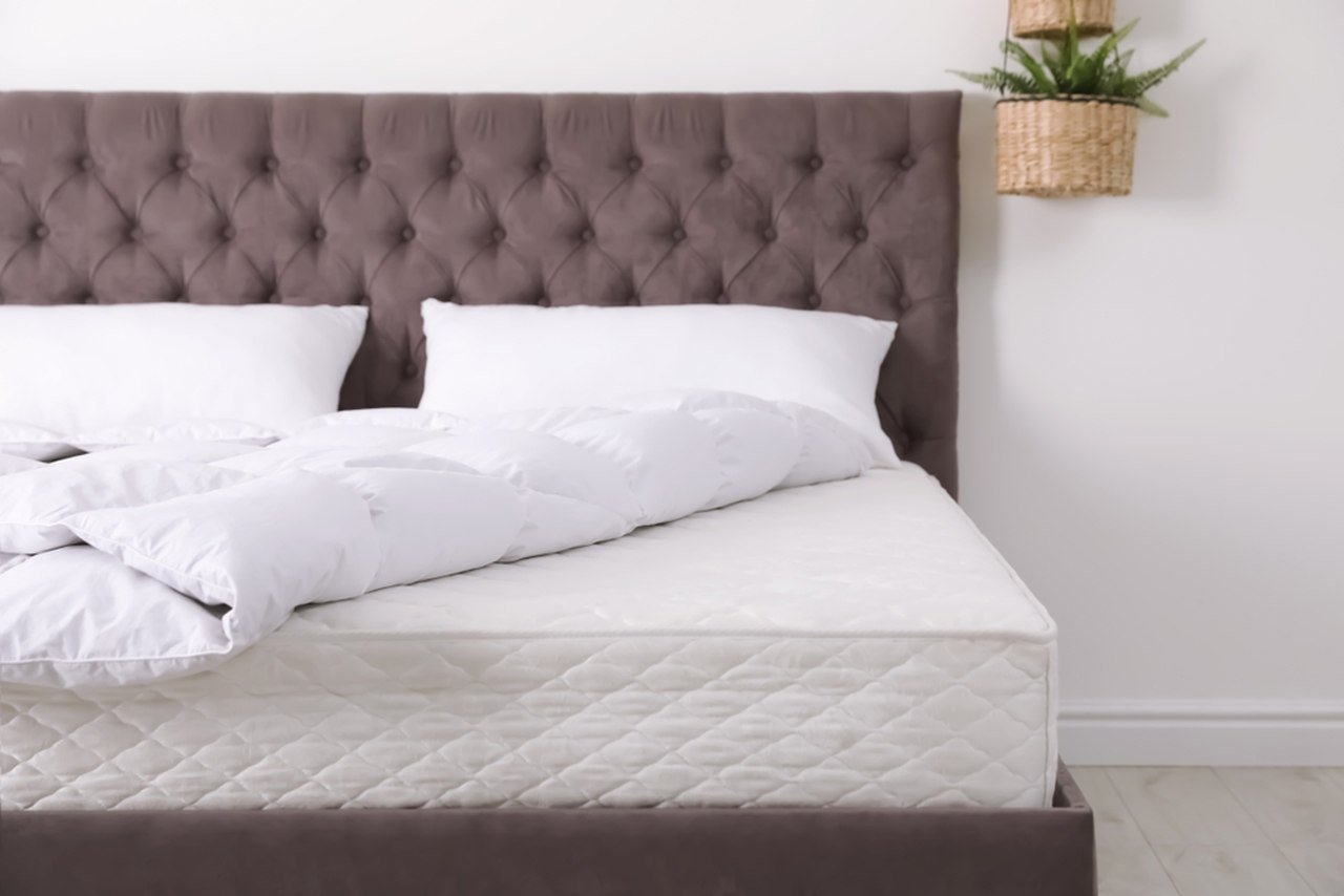 Beyaz örtülü bir yatak ve kahverengi başlıklı baza