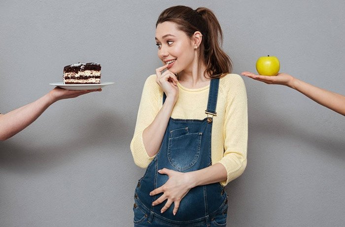 Hamile kadına uzatılan bir dilim pasta ve elma