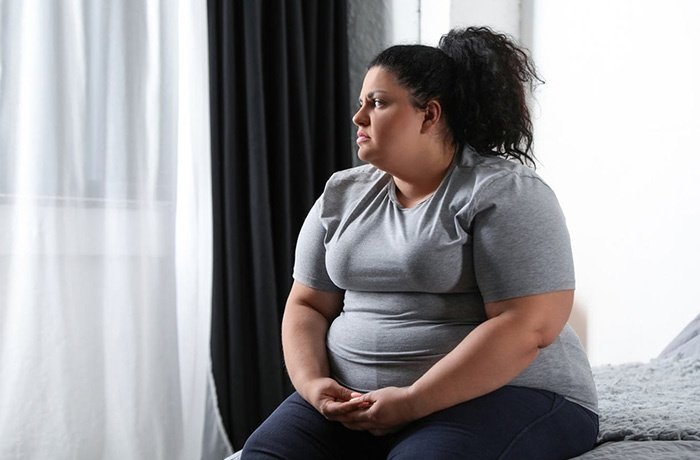 Yatakta oturan kilolu bir kadın
