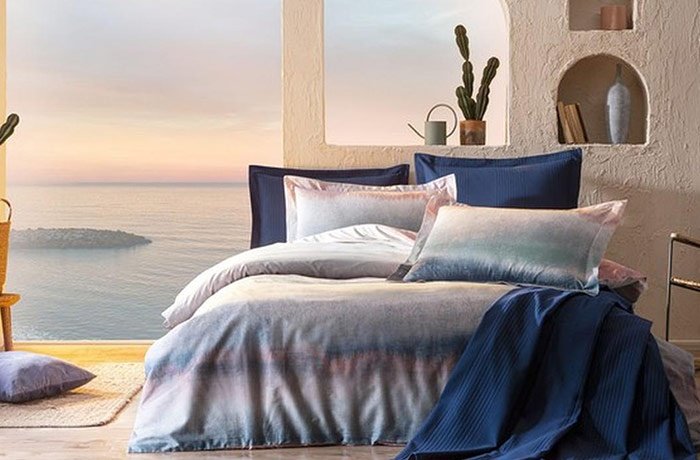 Deniz manzaralı duvar kağıdı ve mavi nevresim takımlı yatak