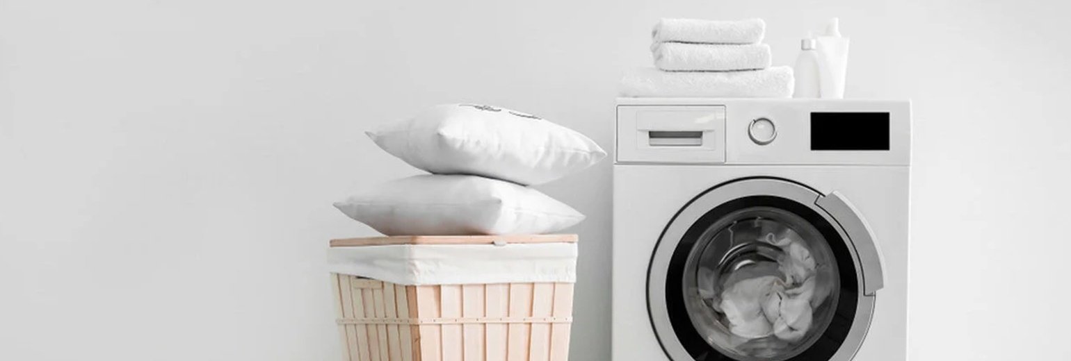 Çamaşır makinesi ve sepetin üstünde iki yastık