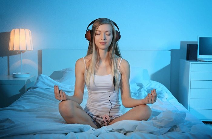 Kulaklık takarak yatakta yoga yapan bir kadın