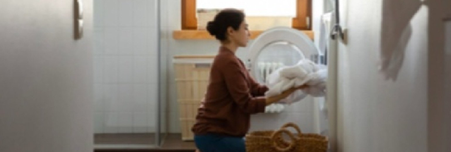 Çamaşır makinesine yorgan atan bir kadın